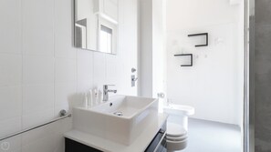 A modern bathroom with a large white sink, a mirror, and a toilet. - Italianway Easy - Amedeo D'aosta 9 (Milan)