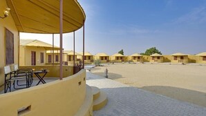Een rij gele gebouwen met een overdekt terras en een geplaveide binnenplaats.