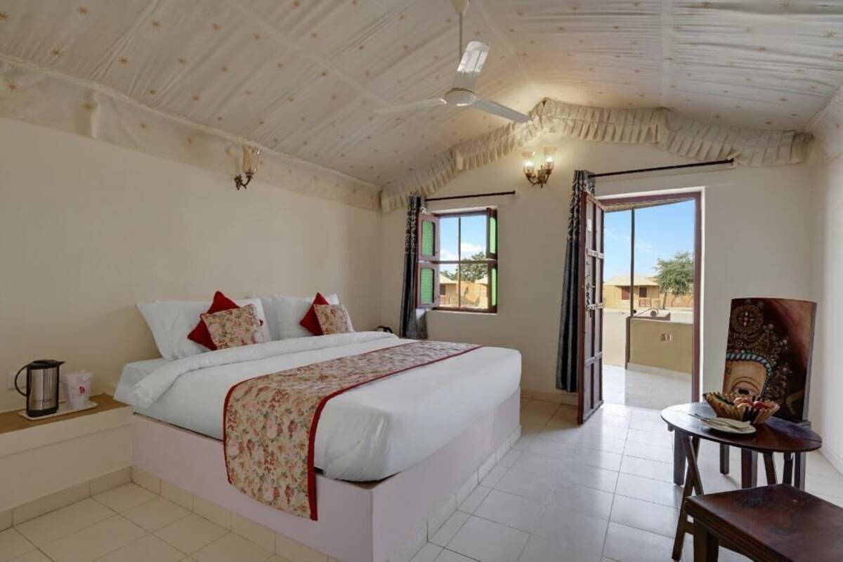 A bedroom with a bed, a ceiling fan, a window, and a view of the outside.