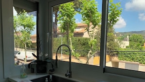 Una cocina con vista a una zona residencial, un lavamanos y una estufa.