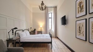 A bedroom with a bed, bedside tables, a lamp, a chair, and framed botanical prints on the wall. - ARCHE KLASZTOR WROCŁAW (Wroclaw)