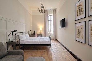 A bedroom with a bed, bedside tables, a lamp, a chair, and framed botanical prints on the wall. - ARCHE KLASZTOR WROCŁAW (Wroclaw)