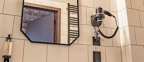A bathroom with a white sink, a mirror, a towel rack, and a wall-mounted telephone.