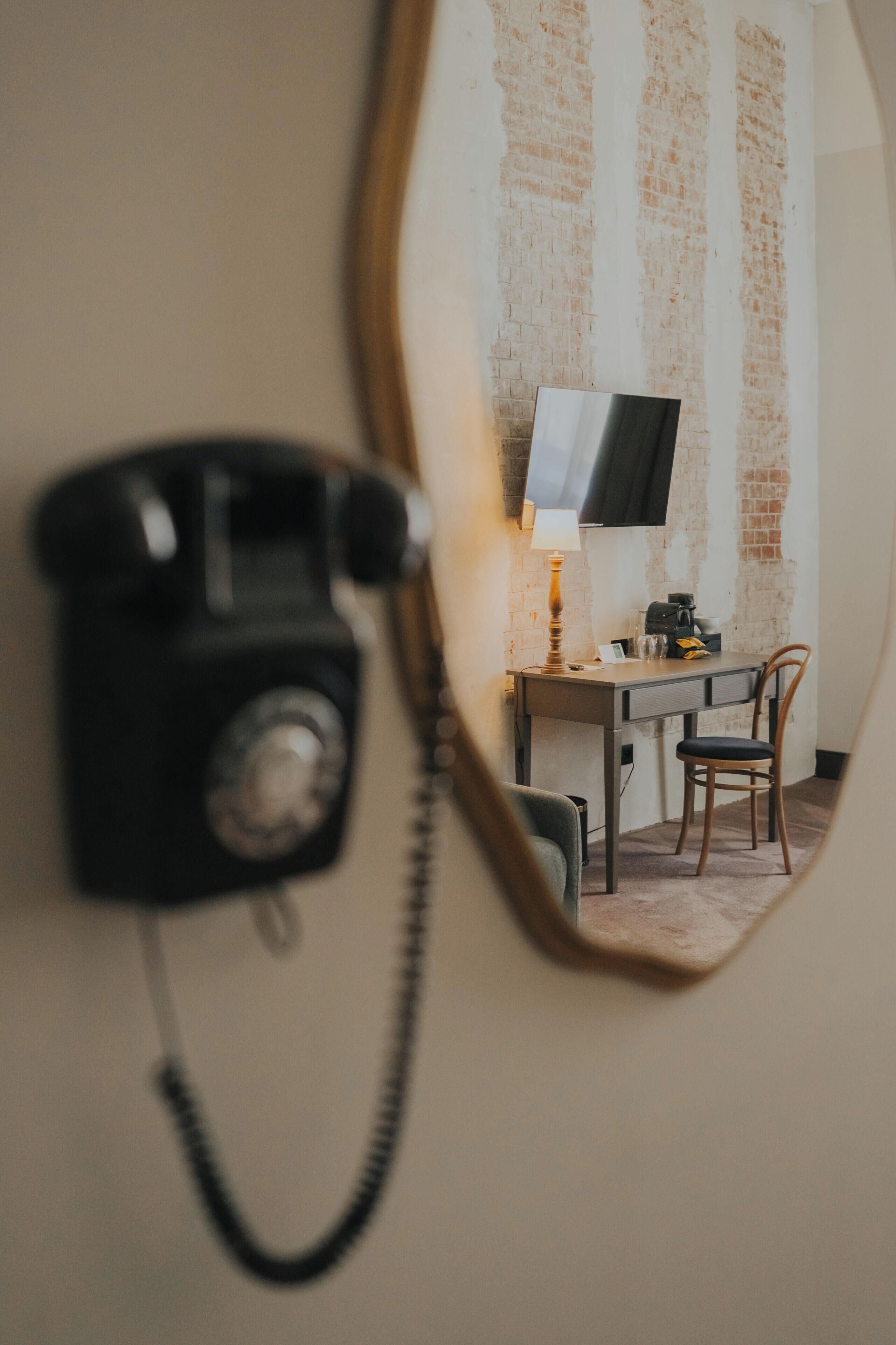 Una habitación con escritorio, silla, lámpara y teléfono.