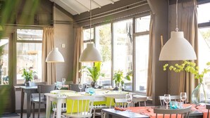 En restaurang med runda bord, stolar och hängande taklampor.