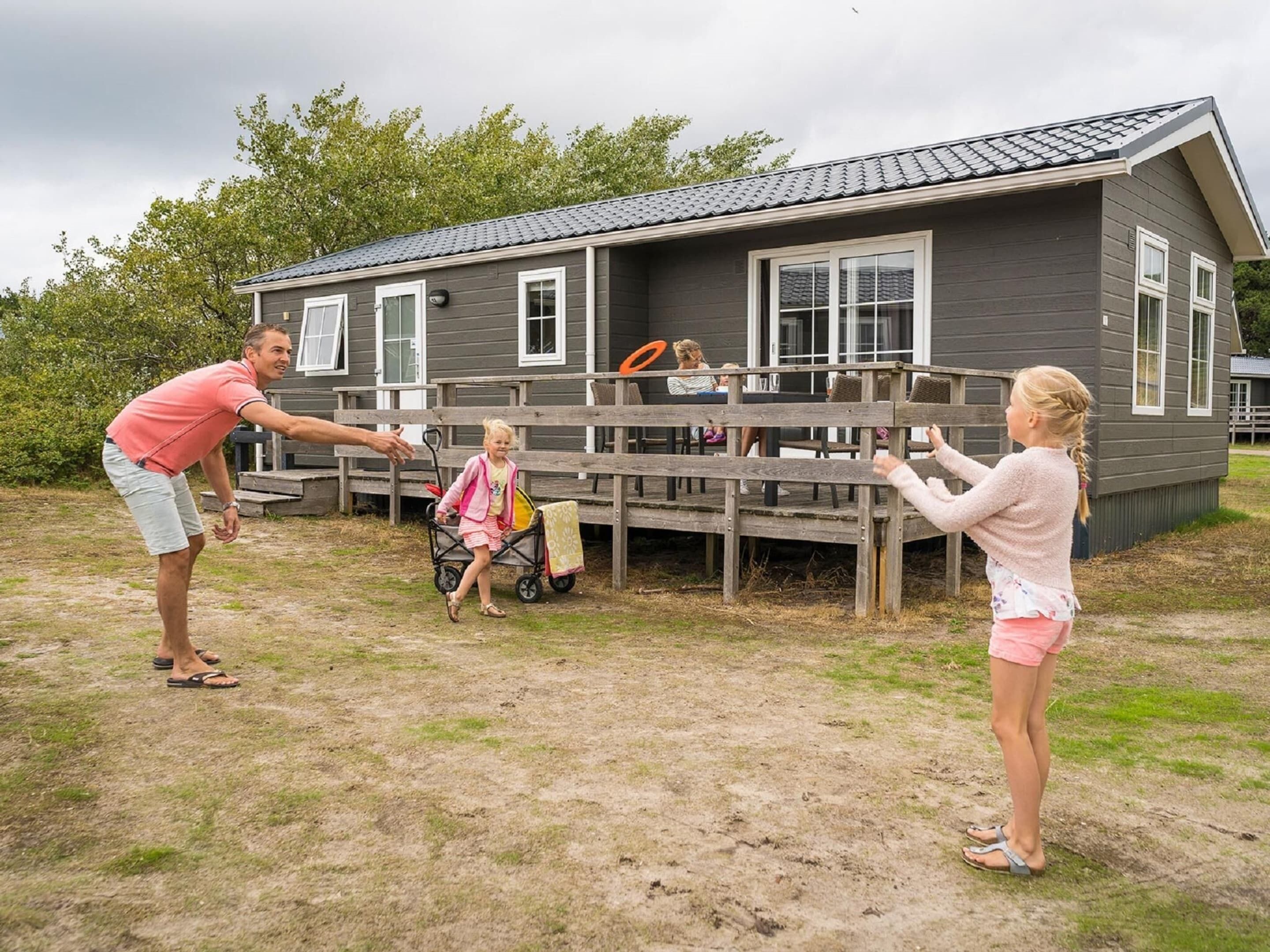 A house with a deck, a child in a stroller, and a person playing with a frisbee.