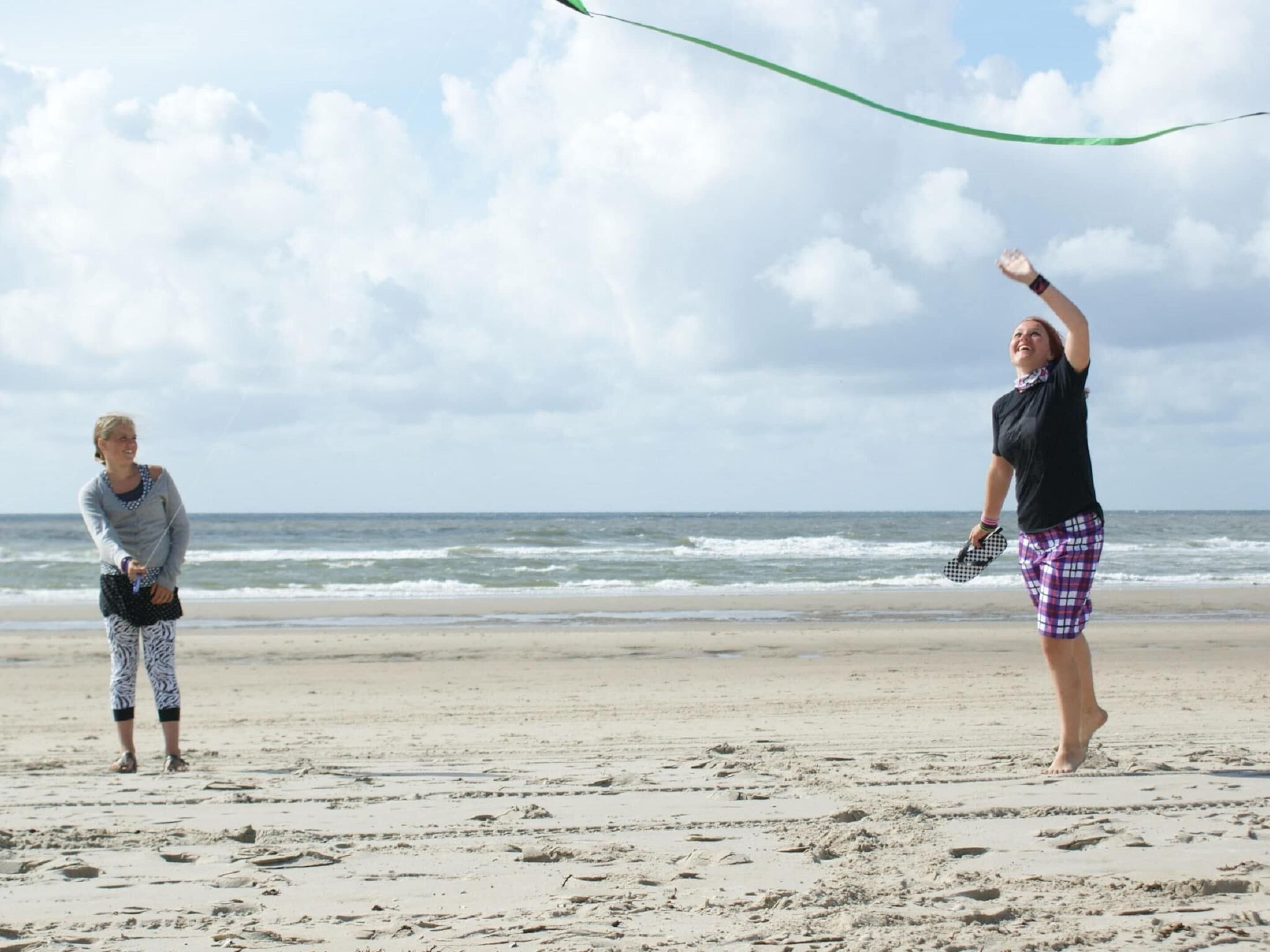 Two people on a beach with a green ribbon in the sky.