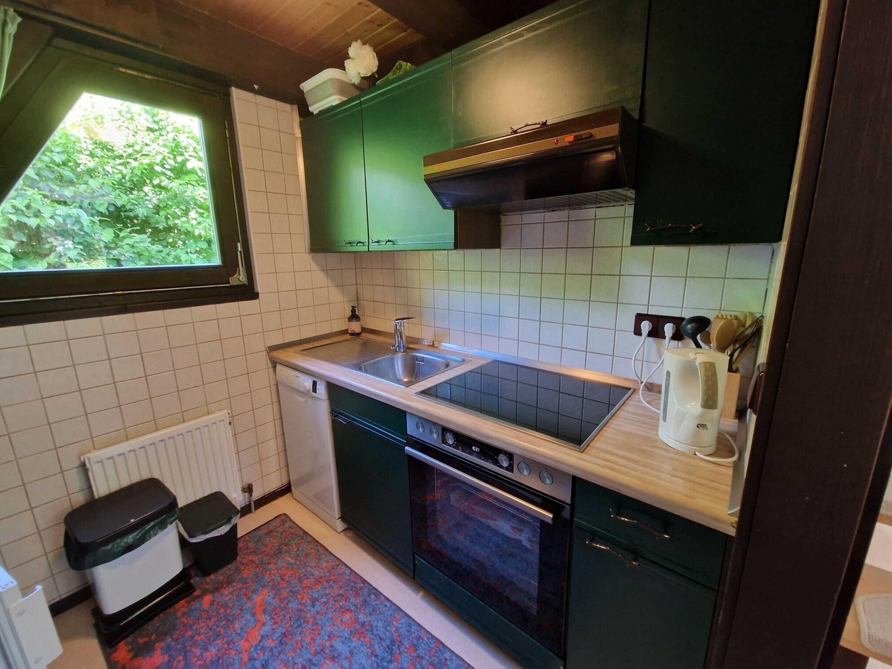 A compact kitchen with a built-in dishwasher, a double sink, and a stove.