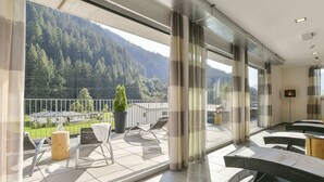 A modern hotel room with a balcony, large windows, and a view of a forested mountain. - Majestic Apartment in Klosterle With Sauna on the Arlberg Met Terras (Klösterle am Arlberg)