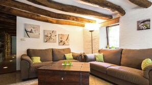 A cozy living room with a brown sofa, a wooden coffee table, and a stone wall. - Tranquil Apartment in Sensenruth With Barbecue (Bouillon)