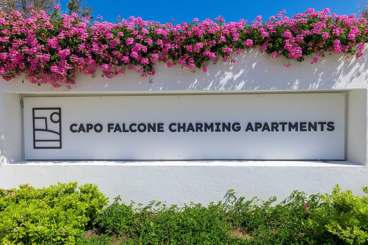 A sign for Capo Falcone Charming Apartments with a clear view of the entrance.