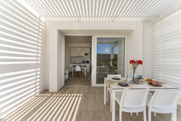 Un espacio habitable moderno y abierto con zona de comedor, cocina y puerta corrediza de vidrio a un balcón.
