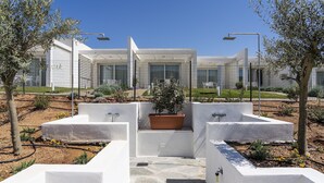 A modern outdoor area with a pathway leading to a seating area, surrounded by white walls and potted plants. - Residence Capo Falcone, Stintino (Stintino)