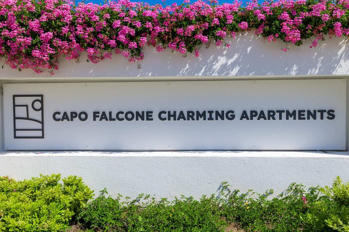 A sign for Capo Falcone Charming Apartments with a bed icon, indicating hotel accommodations.