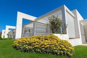 Un bâtiment moderne aux éléments structurels blancs, avec un grand parterre fleuri devant.