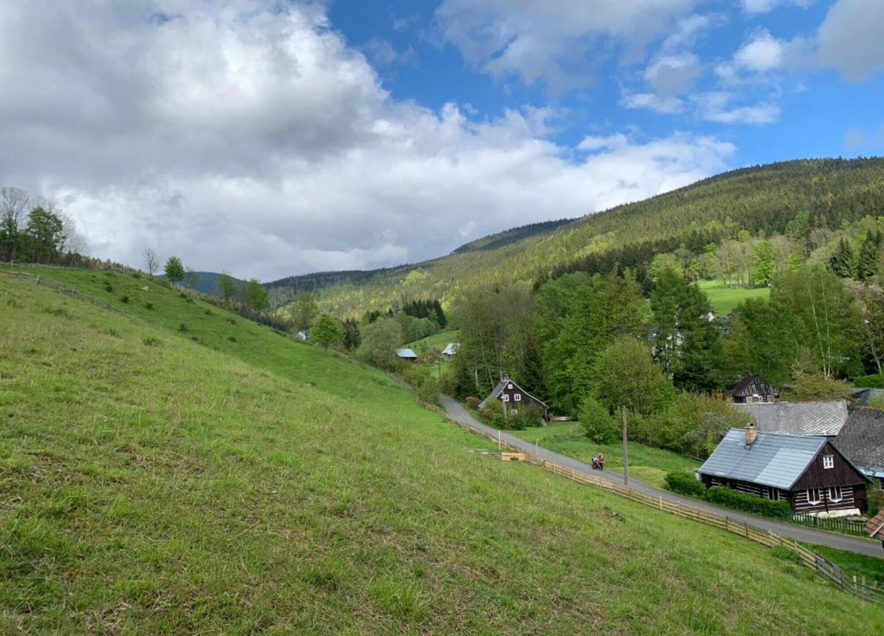 A rural landscape with a road, houses, and a hill.