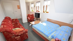 A room with a bed, a sofa, a TV, and a table. - Attractive Apartment in Rokytnice nad Jizerou Near Ski Area (Rokytnice nad Jizerou)