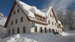 A large, two-story building with a steeply pitched roof covered in snow, surrounded by a snowy landscape. - Attractive Apartment in Rokytnice nad Jizerou Near Ski Area (Rokytnice nad Jizerou)