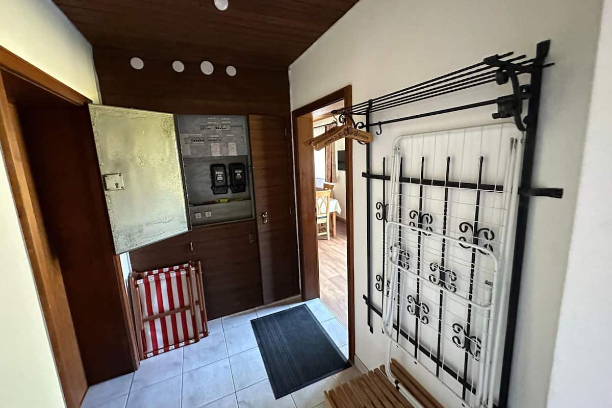 Un couloir avec un radiateur, une porte donnant sur une pièce et un sol carrelé.