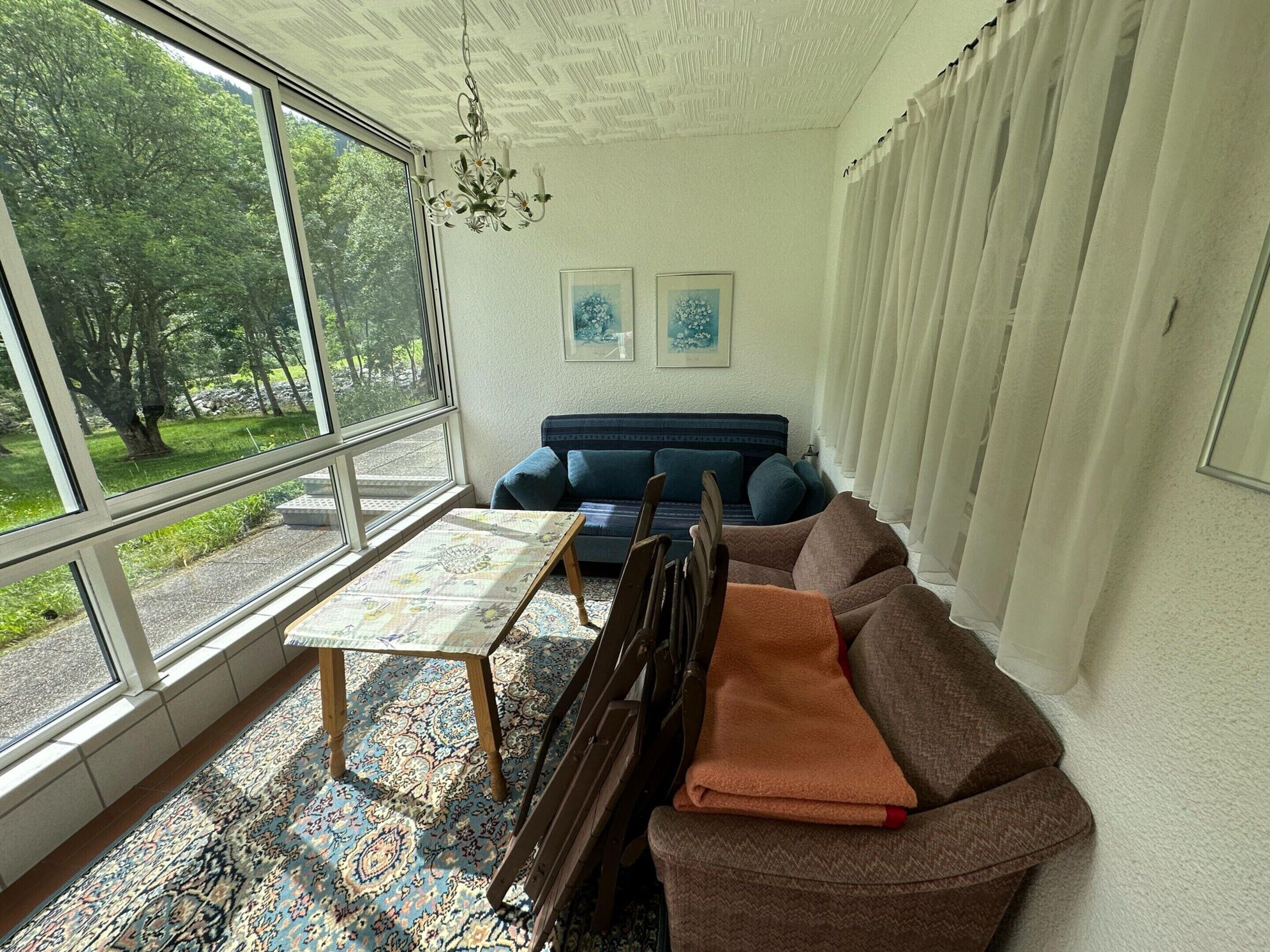 A living room with a sofa, a coffee table, and a view of trees through large windows.