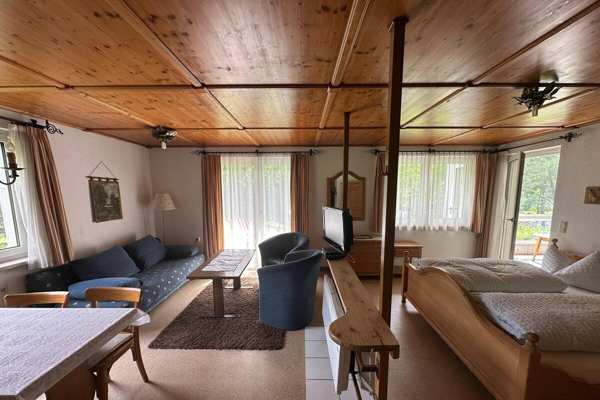 Une pièce confortable avec un plafond en bois, un canapé, un lit, un bureau et un téléviseur.