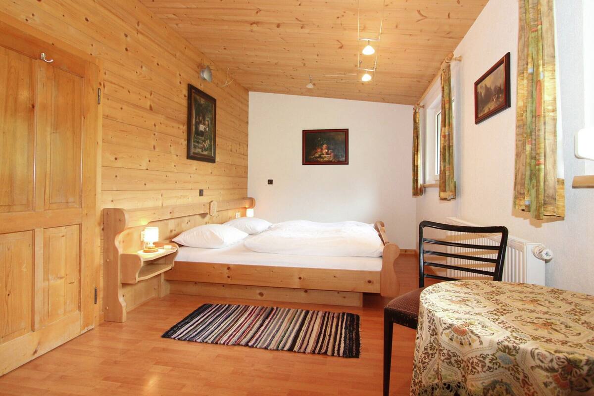 Une pièce dans un chalet en bois, comprenant un lit, une table et une chaise.