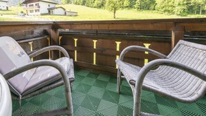 A terrace with wicker chairs and a view of a mountain and houses. - Holiday Home Near ski Resort in St. Gallenkirch (Sankt Gallenkirch)