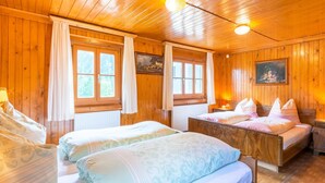 A wooden cabin room with two beds, a painting on the wall, and a window with curtains. - Holiday Home Near ski Resort in St. Gallenkirch (Sankt Gallenkirch)