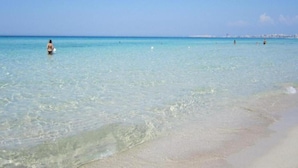 Uma praia com águas turquesa cristalinas e uma extensa faixa de areia.