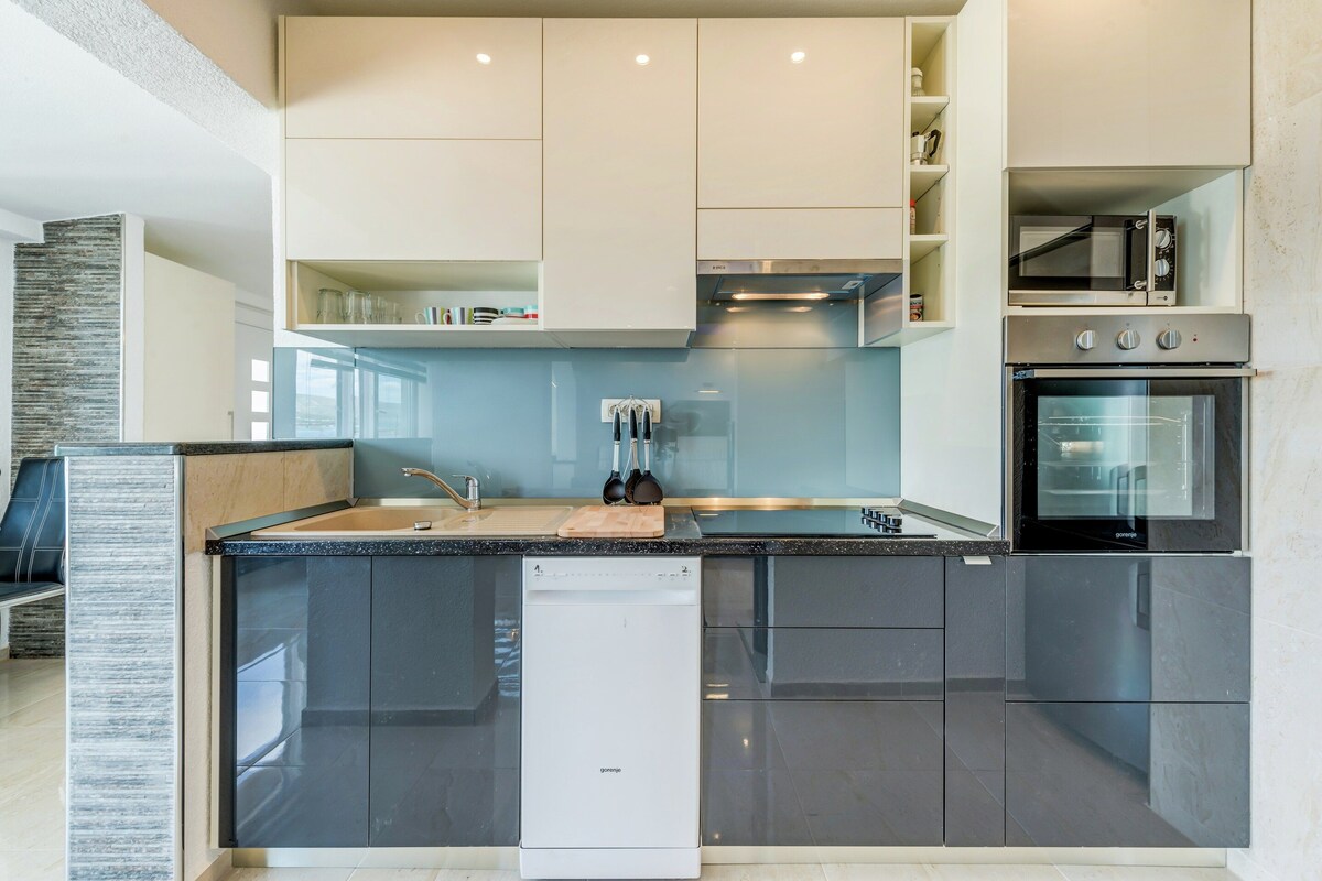 A modern kitchen with a dishwasher, oven, and built-in microwave.