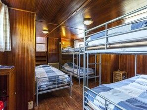 A cabin with bunk beds, wooden walls, a small table, and a radiator.