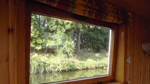 A wooden cabin with a large window overlooking a forested area. - Cozy Boat in Merkem Near Lake (Houthulst)