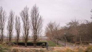 A park with leafless trees, a pathway, and a building in the background. - Cozy Boat in Merkem Near Lake (Houthulst)