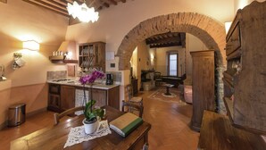 A rustic interior with a wooden dining table, a potted plant, and a brick archway leading to a living area. - Attractive Apartment in Typical Tuscan Style (Figline e Incisa Valdarno)