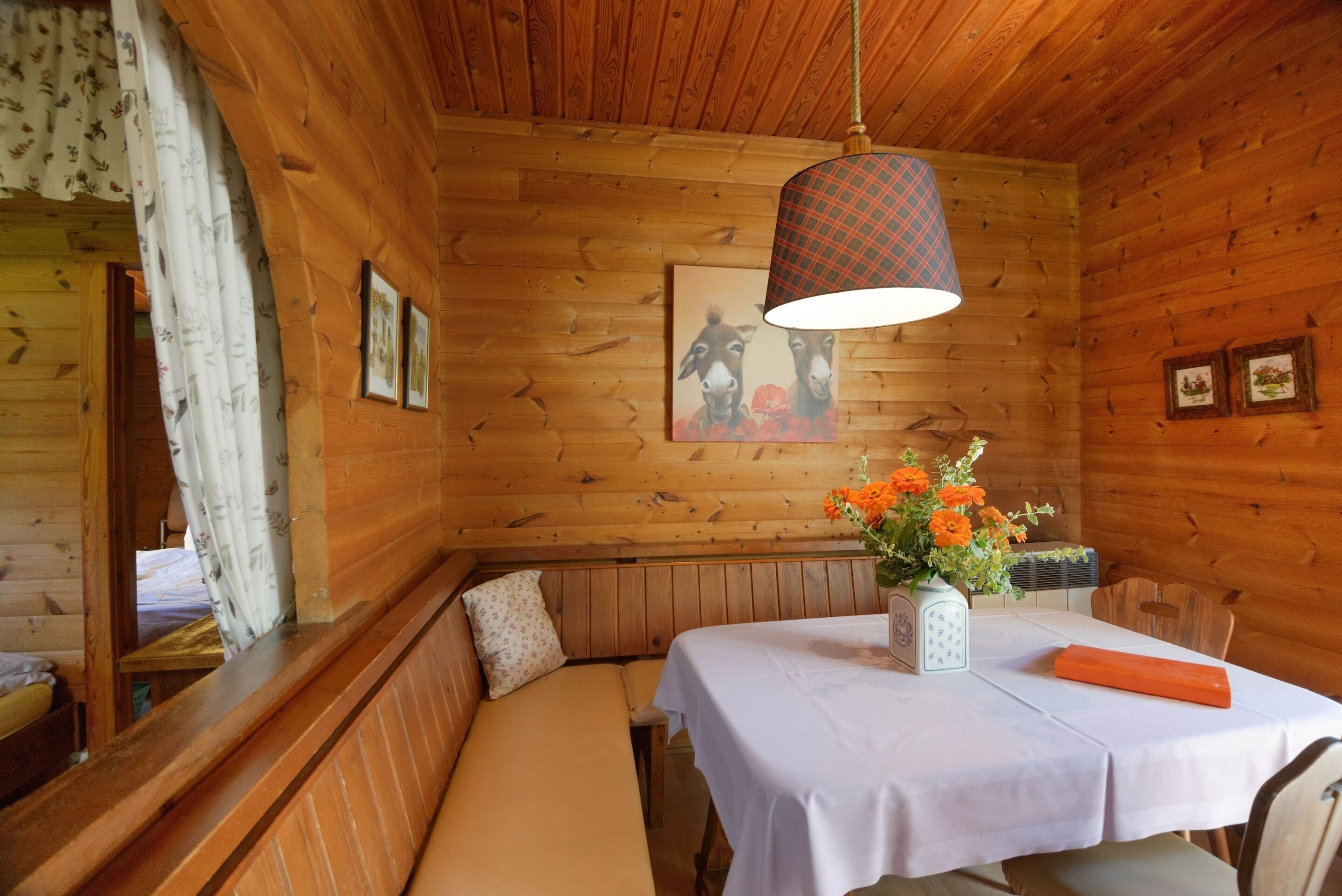 A wooden cabin interior with a bench, table, and hanging lamp.