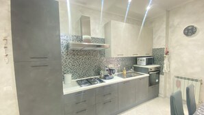 Une cuisine moderne avec des meubles gris, une cuisinière à gaz, un four à micro-ondes et un dosseret carrelé.
