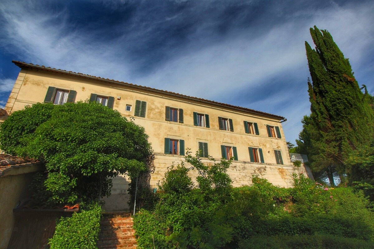 A two-story building with a flat roof, multiple windows with shutters, and a brick wall.