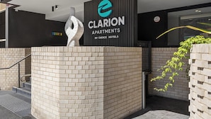 Een moderne entree van een gebouw, met een opvallend bord voor Clarion Apartments by Choice Hotels.