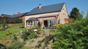 A two-story house with a sloped roof, large windows, and a covered porch.