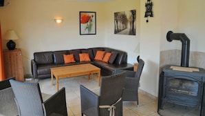 A living room with a sofa, coffee table, wicker chairs, a fireplace, and artwork on the walls.