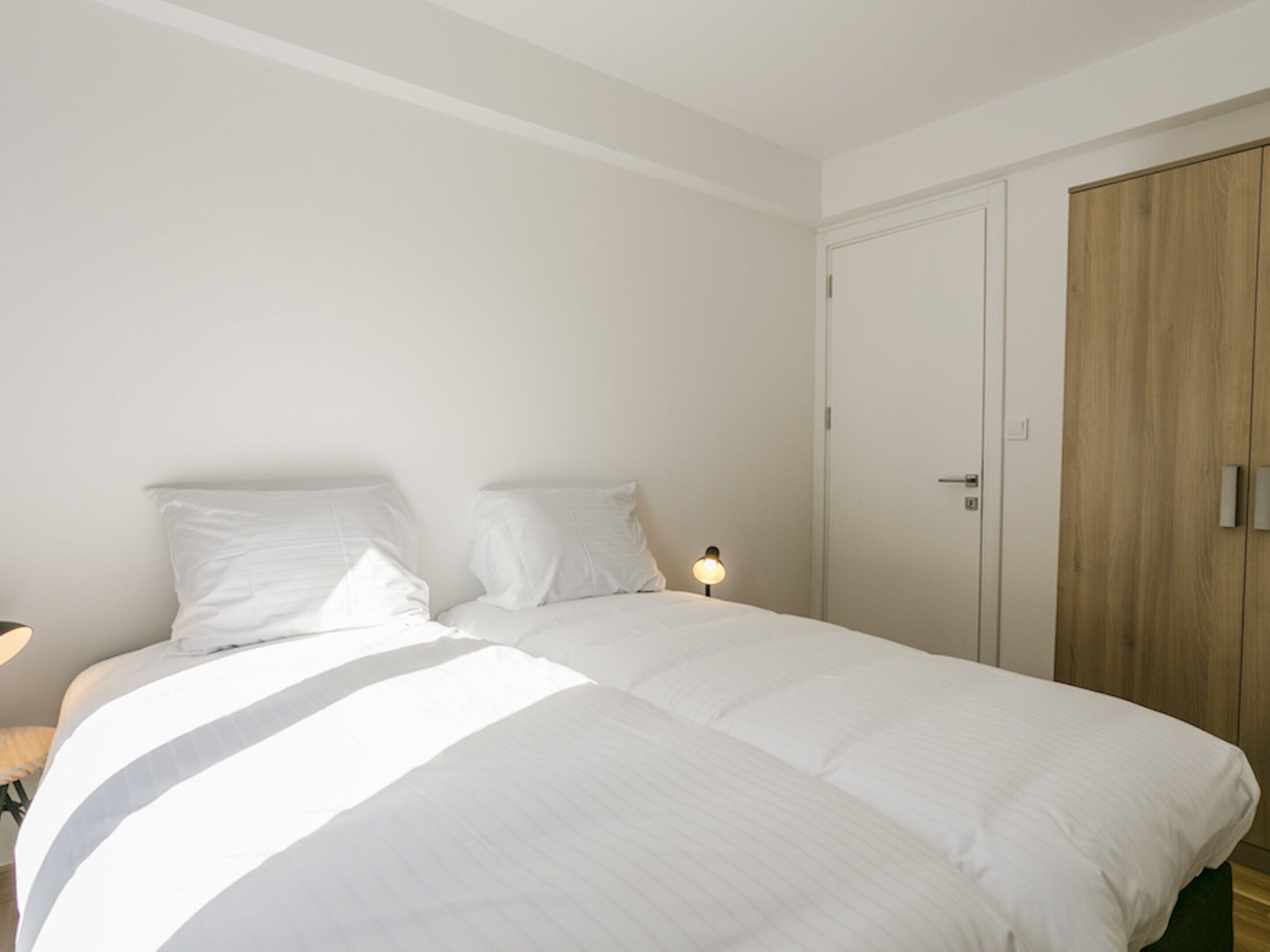 Una camera da letto con un letto grande, due cuscini, una lampada da comodino e un armadio in legno.
