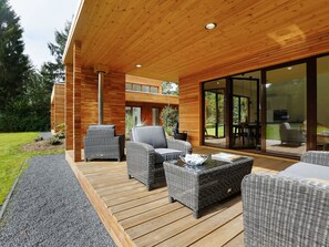 Relax on the spacious deck with comfortable wicker sofas and a small coffee table, surrounded by lush greenery.
