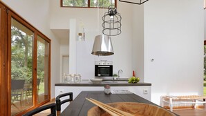 Una cocina moderna con una mesa de comedor de madera, sillas negras y un tazón de madera grande.