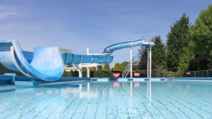 Una piscina con un tobogán acuático azul y un cielo despejado.