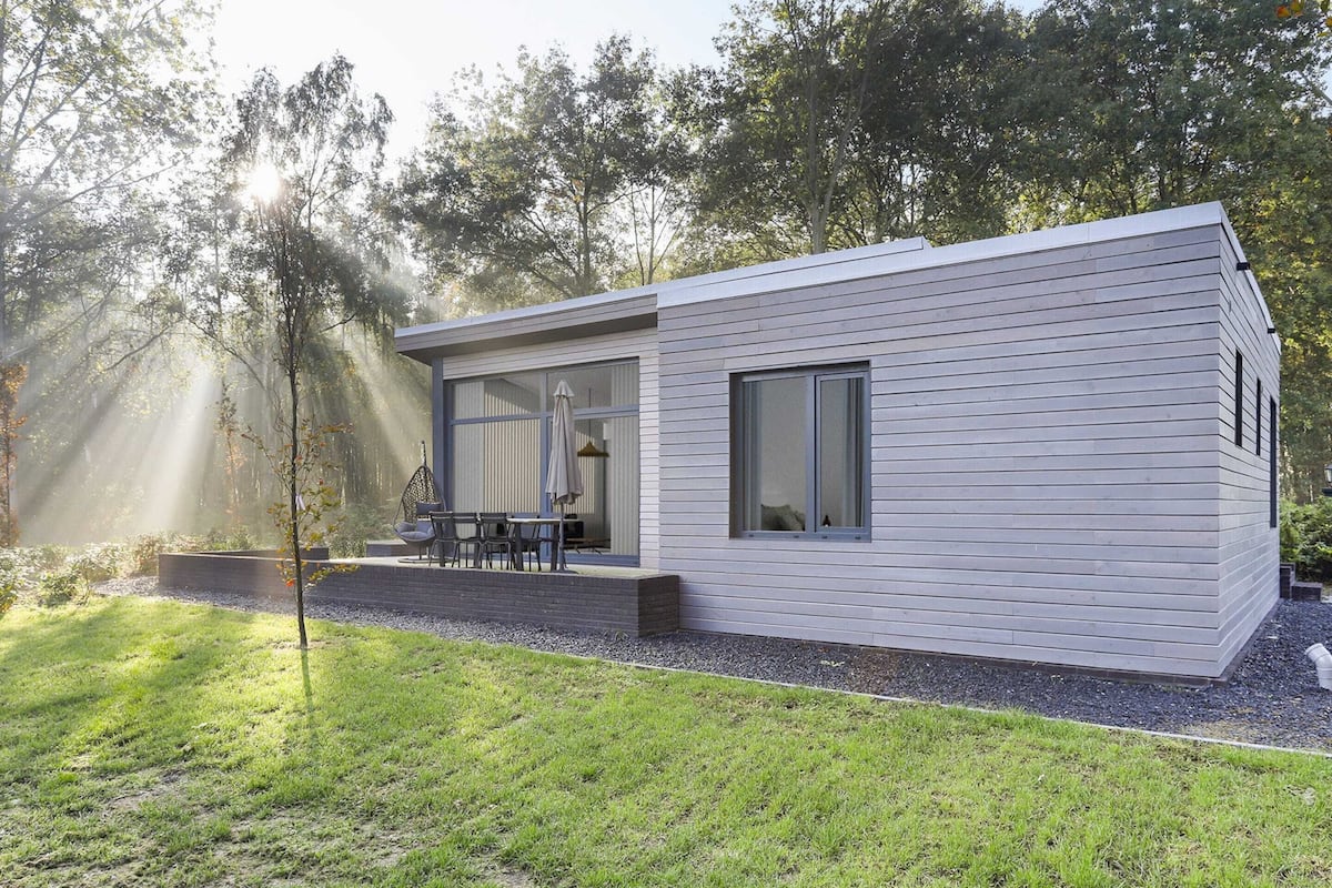 Une maison moderne dotée d’un patio, d’une chaise suspendue et d’une table.