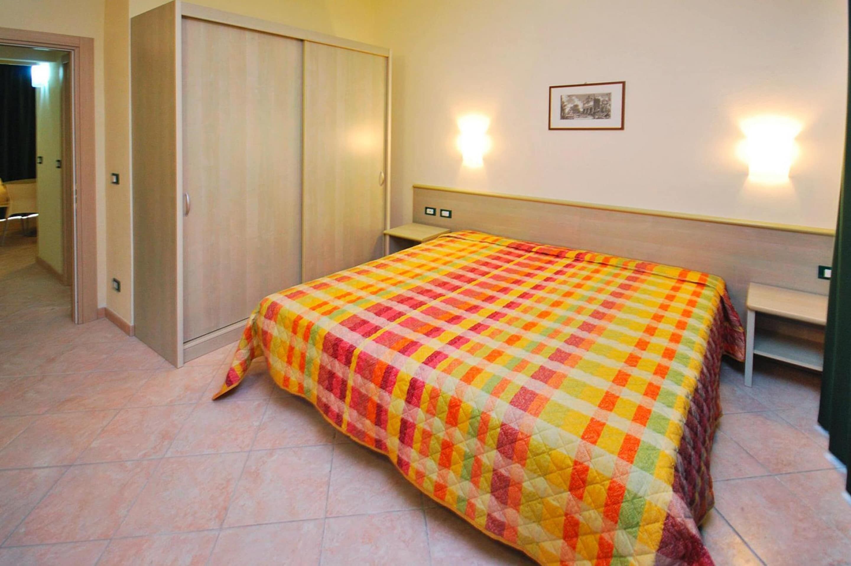Un dormitorio con una cama, un armario y dos luces fijadas a la pared.