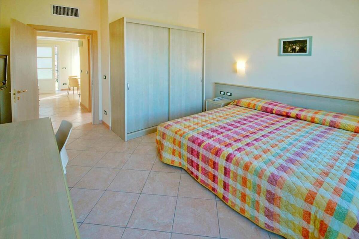 A bedroom with a bed, a wardrobe, a bedside table, and a chair.
