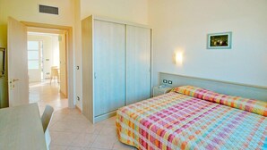 Une chambre à coucher avec un lit, un bureau, une armoire et une chaise.