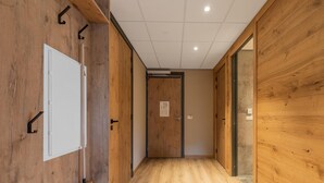 A hallway with wooden walls and a wooden floor, leading to a door with a sign. - Comfortable Apartment in Egmond aan Zee Near Sea (Egmond aan Zee)