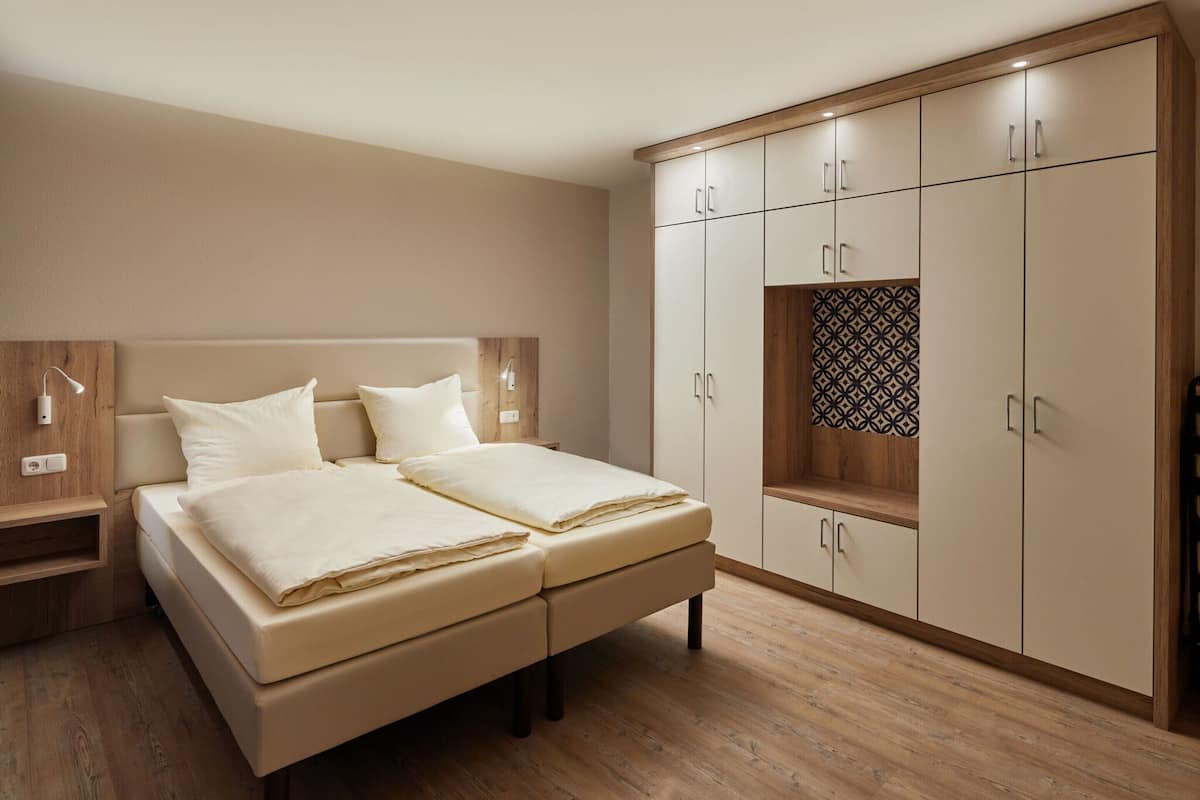 A bedroom with a bed, bedside tables, a wardrobe, and a nightstand.